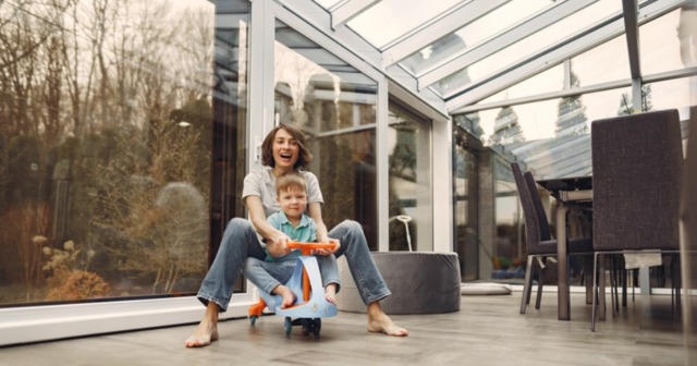 A happy mother and child enjoying natural light in a sunroom with energy-efficient glass windows.