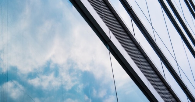 A modern glass building featuring insulated glass panels reflecting the sky for energy efficiency and aesthetic appeal.