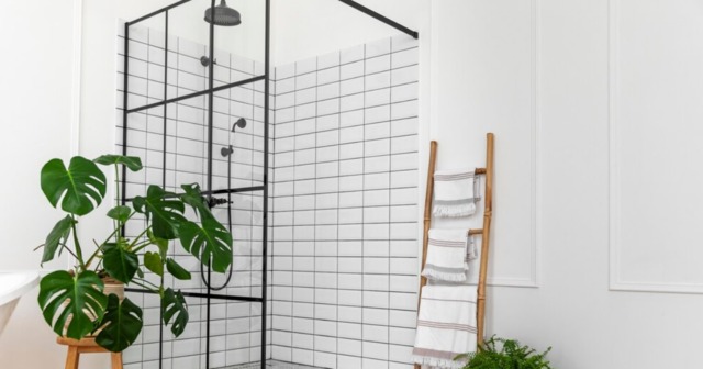 Modern shower cubicle with black metal framing and white subway tiles.