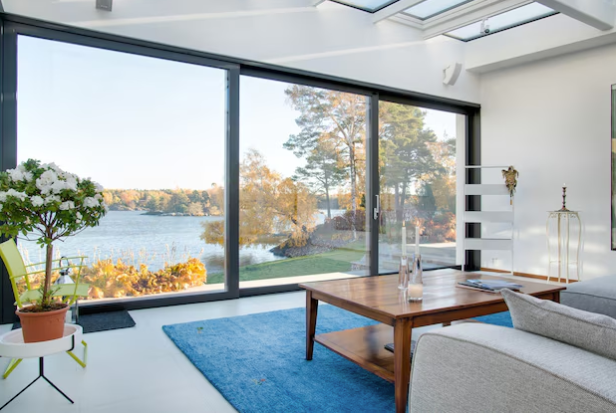 A modern living room with large energy-efficient glass windows offering a scenic outdoor view and natural lighting.
